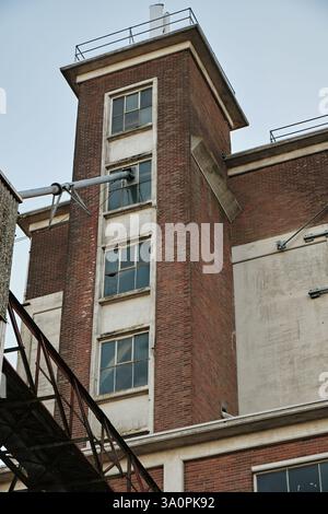 Ein historisches Getreidesilo mit roter Ziegelfassade, verwitterten Betondetails und kaputten Fenstern, die den industriellen Verfall und die Verlassenheit der Stadt zum Ausdruck bringen. Stockfoto