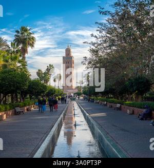 Marrakesch, Marokko - 18. Februar 2025: Besucher schlendern durch üppige Gärten und bewundern die Koutoubia-Moschee in Marrakesch. Stockfoto