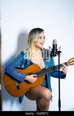 Junge Musikerin singt und spielt Akustikgitarre im Tonstudio Stockfoto