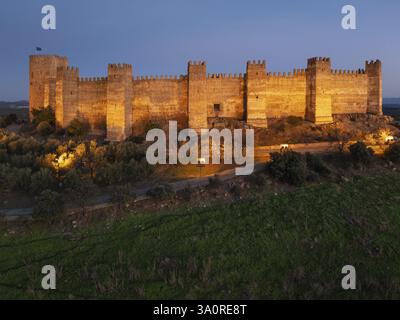Das beeindruckende maurische Burgalimar-Schloss in der Stadt Banos de la Encina. Bei Dämmerung mit Flutlicht. Luftaufnahme. Drohnenaufnahme. Provinz Jaen, Andalusien, Spa Stockfoto