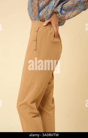 Eine Serie von Studiofotos eines jungen weiblichen Models mit einfachen beigefarbenen Hosen mit Zigaretten Stockfoto