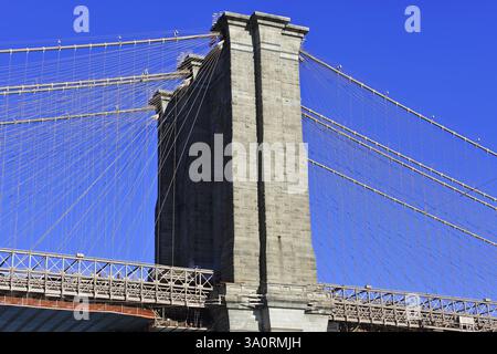 Brooklyn Bridge in Brooklyn, Manhattan, New York, detaillierte Ansicht einer Brückenkonstruktion mit massiven Steinsäulen und Kabeln unter klarem Himmel, New Stockfoto