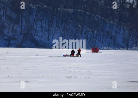 Webster, NY, USA - 22. Februar 2025 - Eisfischer fischen an einem saisonalen Wintertag in Upstate New York ohne Unterschlupf. Stockfoto
