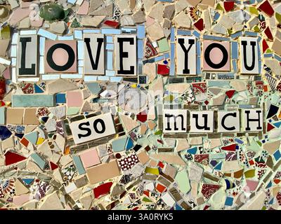 Eine Nahaufnahme eines wunderschön gearbeiteten Mosaiks mit den Worten „LOVE YOU SO MUCH“. Das Mosaik besteht aus verschiedenen kleinen, bunten Fliesen Stockfoto