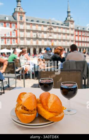 Gebratene Tintenfische Sandwich und Kartoffel-Tortilla-Sandwich mit Gläser Rotwein auf der Terrasse. Der Hauptplatz, Madrid, Spanien. Stockfoto