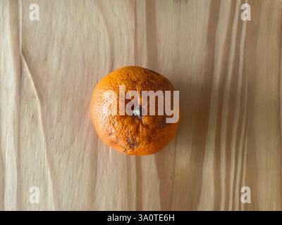 Mandarin Orange teilweise frisch und teilweise überreif und schimmelig auf einer Holzoberfläche in Natural Lightning Stockfoto