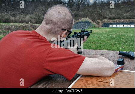 Mann feuert eine Angriffswaffe auf Papierziele ab Stockfoto