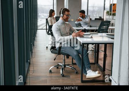 Online-Unterhaltung. Männer und Frauen arbeiten zusammen im Büro. Stockfoto