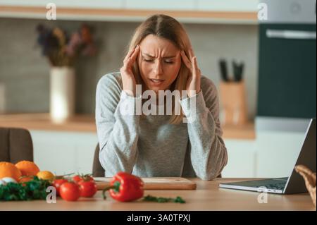 Müde, Kopfschmerzen. Die schöne junge Frau ist in der Küche. Stockfoto