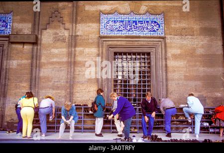 Türkei, Istanbul. Touristen ziehen ihre Schuhe aus, um die Blaue Moschee zu besuchen - so genannt wegen der Dekoration mit blauen Keramikfliesen aus Iznik. It Stockfoto