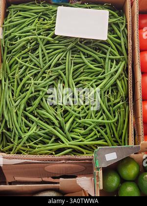 Grüne Bohnen zum Verkauf auf dem Bauernmarkt. Pappschachteln mit frischem, farbenfrohen Gemüse. Stockfoto
