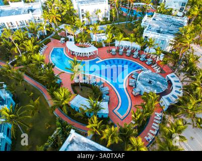 Blick aus der Vogelperspektive auf ein tropisches karibisches Hotel Resort Villas, Swimmingpool mit Liegestühlen und Palmengarten Dominikanische Republik Stockfoto