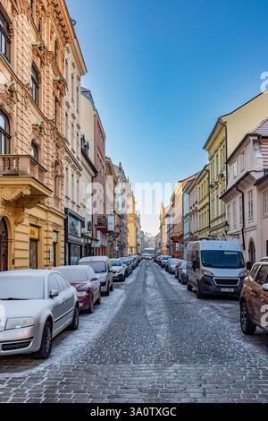 Pilsen, Tschechische Republik - 2. Januar 2020: Alte historische Straße mit alten Gebäuden im Winter in der Altstadt von Pilsen mit Parkplätzen im Schnee. Stockfoto