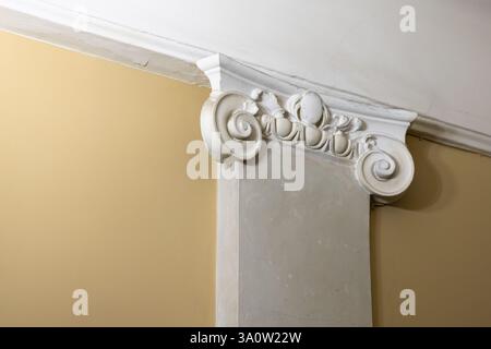 Klassisches Portikusfragment mit weißer Säulenspitze und gelber Wand. Beispiel für antike klassische Architektur Stockfoto