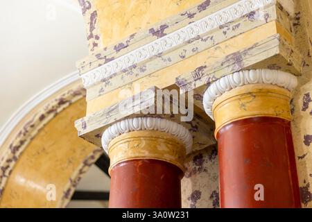 Rote Steinsäulen mit gelben weißen Kapitellen sind unter der Decke, Hintergrundfoto der klassischen Architektur Stockfoto
