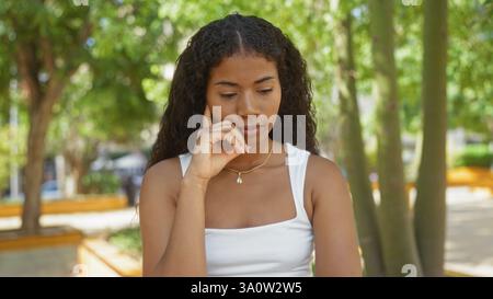 Junge Frau, die tief in einem Stadtpark an einem sonnigen Tag denkt Stockfoto