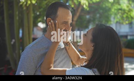 hispanische Paare mittleren Alters, die einen liebevollen Moment in einem Outdoor-Stadtpark genießen, umgeben von Grün, verkörpert Familie und Zweisamkeit. Stockfoto