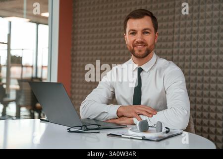 Ein gutaussehender Mann in formeller Kleidung arbeitet mit dem Laptop im Büro. Stockfoto