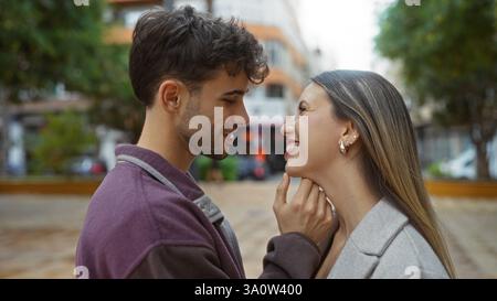 Mann und Frau lächeln sich in einem urbanen Park an, fangen die Essenz eines wunderschönen Paares in einer urbanen Umgebung ein und vermitteln einen Stron Stockfoto