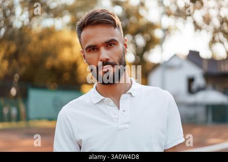 Wunderschönes Porträt. Junger Mann ist tagsüber auf dem Tennisplatz. Stockfoto