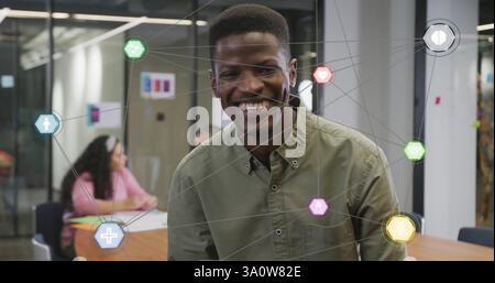 Bild von Mediensymbolen über birassischem Geschäftsmann, der im Büro lächelt Stockfoto