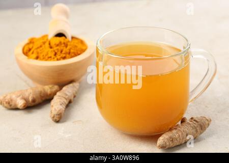 Aromatischer Kurkuma-Tee, Rhizome und Pulver auf weißem texturiertem Tisch, Nahaufnahme Stockfoto