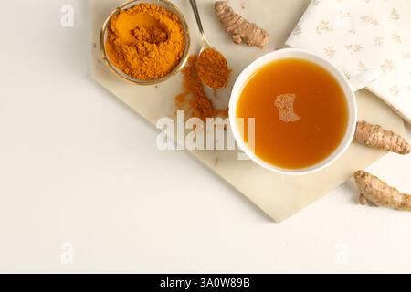 Aromatischer Kurkuma-Tee, Pulver und Rhizome auf weißem Tisch, flach gelegen. Leerzeichen für Text Stockfoto