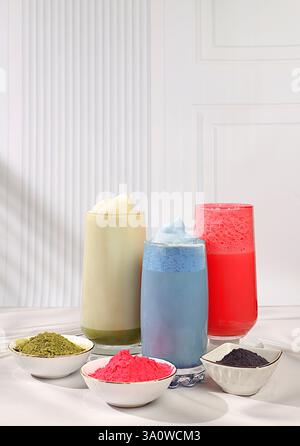 Auswahl verschiedener Matcha-Tee-Latte mit Milch auf elegantem, sonnigem Hintergrund der Küche und Matcha-Pulver. Traditionelles indisches Getränk reich an Antioxidantien Stockfoto