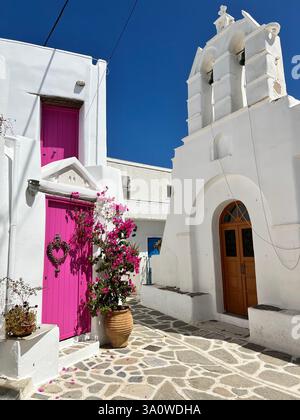 Ein malerisches griechisches Dorf mit einer weißen Kirche, rosa Tür und blauem Himmel Stockfoto