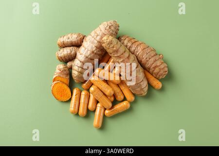Kurkuma-Rhizome und -Kapseln auf grünem Hintergrund, flache Lagen Stockfoto
