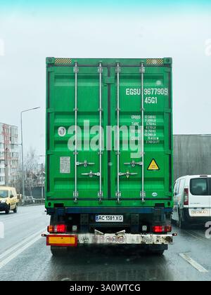 Kiew, Ukraine - 4. März 2025: Ein umweltfreundlicher Lieferwagen, der einen Frachtcontainer auf einer nassen Straße von hinten gefangen nimmt Stockfoto