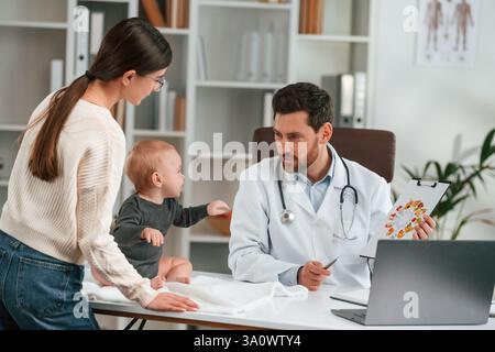 Beratung. Mit Baby und Mutter. Der Arzt in formeller Kleidung arbeitet im Schrank. Stockfoto