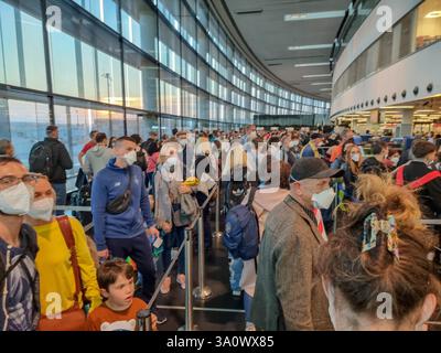 Fluggäste / Menschen mit Gesichtsmasken stehen am Flughafen Wien in Warteschlangen; überfülltes Flughafenterminal, Warteschlangen, Wartezeiten, Check-in-Warteschlangen Stockfoto