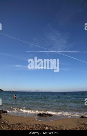 Jet Trails im Sky Vouliagmeni Beach Griechenland Stockfoto