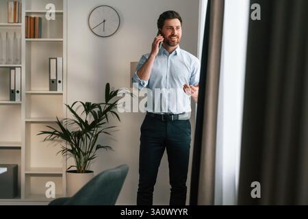 Mit Telefon. Der Arzt in formeller Kleidung arbeitet im Schrank. Stockfoto