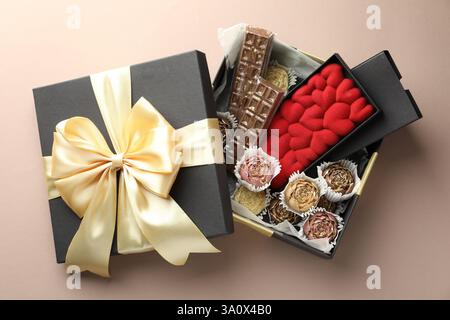 Verschiedene köstliche Schokoladenbonbons in Box auf beigem Hintergrund, Blick von oben Stockfoto