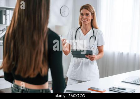 Stehen, Ratschläge geben, Notizblock halten. Eine junge Frau bei einem Termin für einen Ernährungsberater. Medizinische Versorgung. Stockfoto