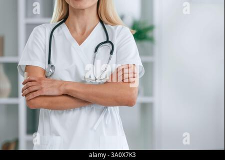 Nahansicht. Mit Stethoskop. Die junge Ärztin im weißen Mantel ist drinnen. Stockfoto