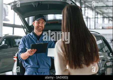 Die junge Frau besucht den Automechaniker in der Garage. Reparaturservice. Stockfoto