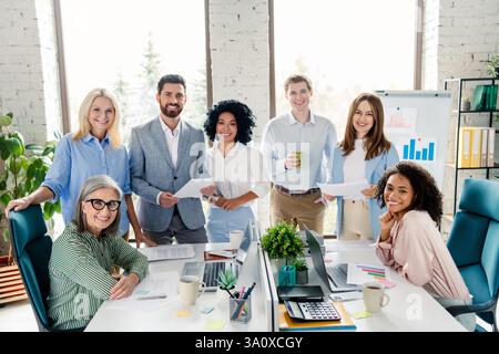 Vielfältige Geschäftsteams arbeiten in modernen Büroumgebungen mit Papieren und Datendiagrammen zusammen Stockfoto