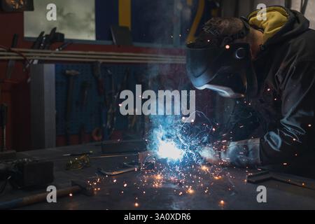 Erfahrener, erfahrener Arbeiter, der in einer Werkstatt arbeitet und beim Schweißen von Metallmaterialien Funken erzeugt. Industriekonzepte. Stockfoto