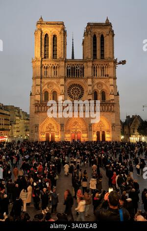 Der Blick in die Dämmerung auf die Kathedrale Notre-Dame de Paris mit Besuchern, die in der Schlange stehen, um das Innere der Kathedrale im Vordergrund zu besuchen. Paris Frankreich Stockfoto