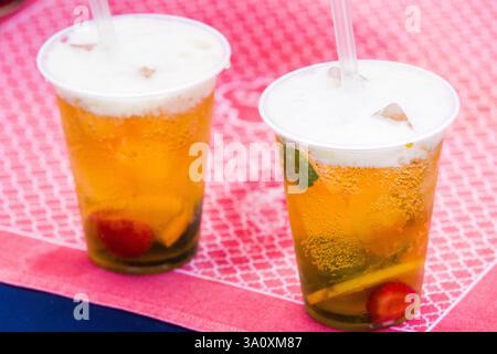 Zwei Eisgetränke mit Obst und Minze, wahrscheinlich ein mit Früchten angereichertes Bier, auf einer Straßenmesse. Pinkfarbene Tischdecke. Stockfoto