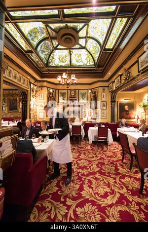 Kellner serviert Abendessen im Rules Restaurant, London, Großbritannien. Verzierte Buntglasdecke. Kulinarisches Erlebnis. Stockfoto