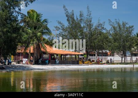 Blick aus der Nähe auf den südöstlichen Strand von Praia dos Nobres in der Araruama Lagune mit gekachelten Dachhütten unter einem heißen sonnigen, klaren blauen, warmen Sommermorgen Himmel. Stockfoto