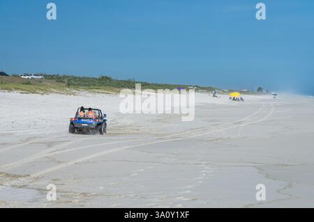 Ein blauer Buger-Dünen-Buggy überquert den fast einsamen Strand Praia Seca mit weißem Sand unter einem ruhigen, klaren, heißen Sommernachmittag mit sonnigem blauem Himmel. Stockfoto