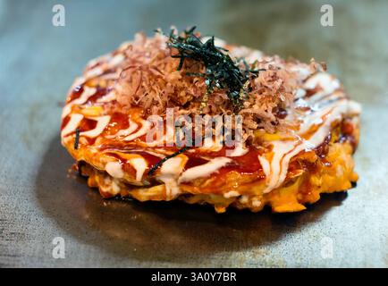 Küchenchef Masanobu Nishikura kocht am 20. Juli 2017 Okonomiyaki-Pfannkuchen auf der Grillplatte im Hauptgeschäft von Boteju in Osaka, Japan. ROB GILHOOLY FOTO Stockfoto