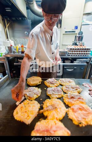 Küchenchef Masanobu Nishikura bestreut am 20. Juli 2017 im Hauptgeschäft von Boteju in Osaka, Japan, heiße Okonomiyaki-Pfannkuchen. ROB Stockfoto