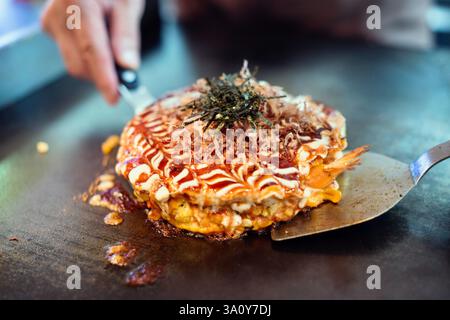 Küchenchef Masanobu Nishikura serviert am 20. Juli 2017 im Restaurant Boteju in Osaka, Japan, mit teko-Spateln einen Okonomiyaki-Pfannkuchen. Stockfoto