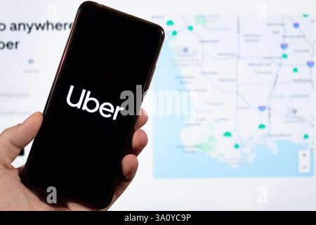 BOGOTA, KOLUMBIEN - 05. MÄRZ 2025 ein Smartphone mit uber App-Logo und unscharfer Social-Media-Oberfläche im Hintergrund Stockfoto